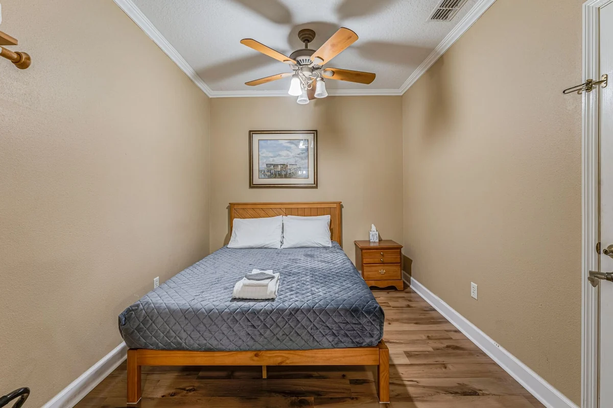 Chaz River Suite sleeping room with a bed, wooden bedside tables and a ceiling fan