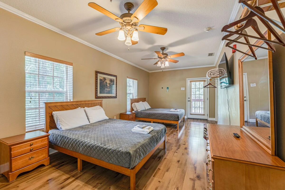 Crystal River Suite bedroom with two beds, wood floors and a door opening toward the veranda