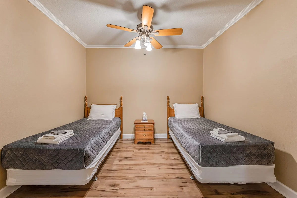 Hotel bedroom with two single beds, a wooden nightstand between them and a ceiling fan